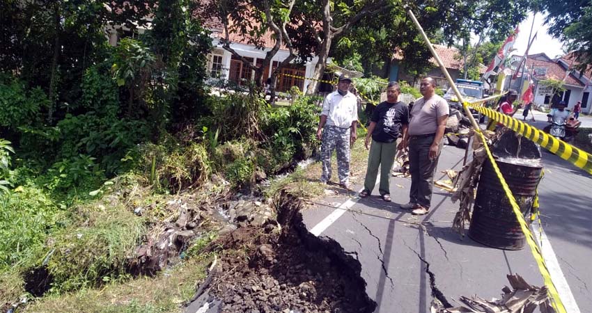 Kapolsek Sumberbaru AKP Subagiyo meninjau lokasi jalan yang ambrol dan memberikan tanda peringatan. (ist)